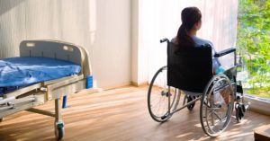 Woman in the wheel chair in hospital looking out the window