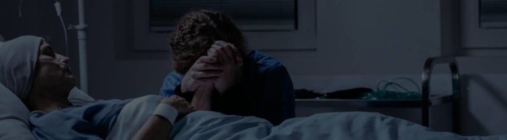 woman grieving next to hospital bed