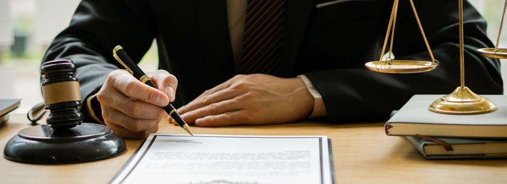 Lawyer with pen explaining document next to gavel and scales