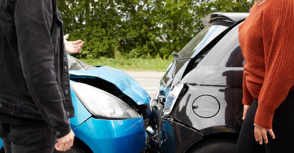 Two drivers in auto accident looking at the damages