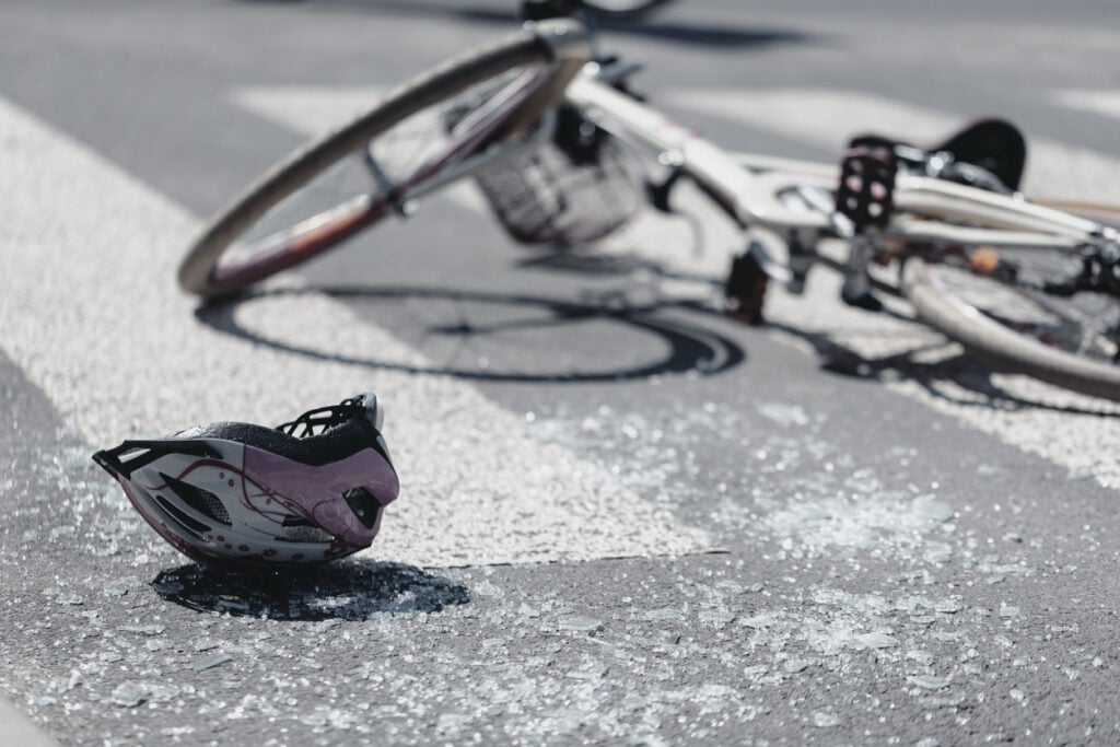 A broken bicycle and helmet laying in the street after a bike accident