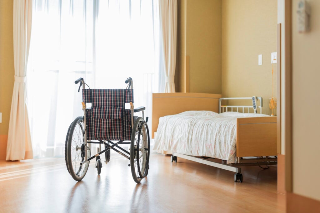 A wheelchair in an empty nursing home bedroom