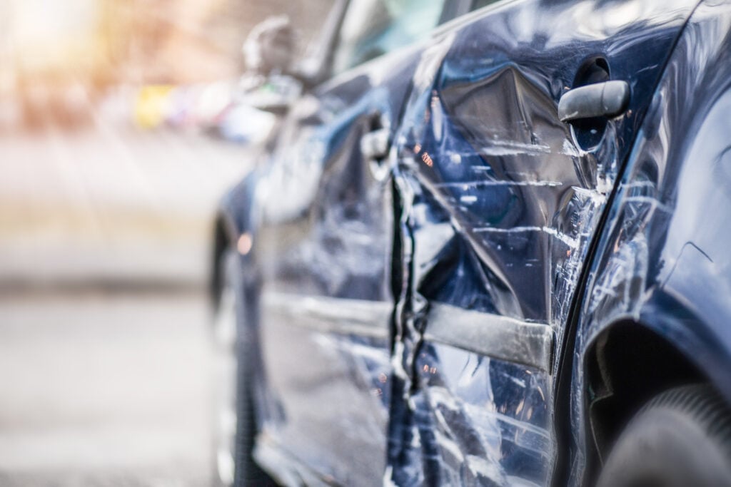 The dented and scraped side of a car that has been in an auto accident