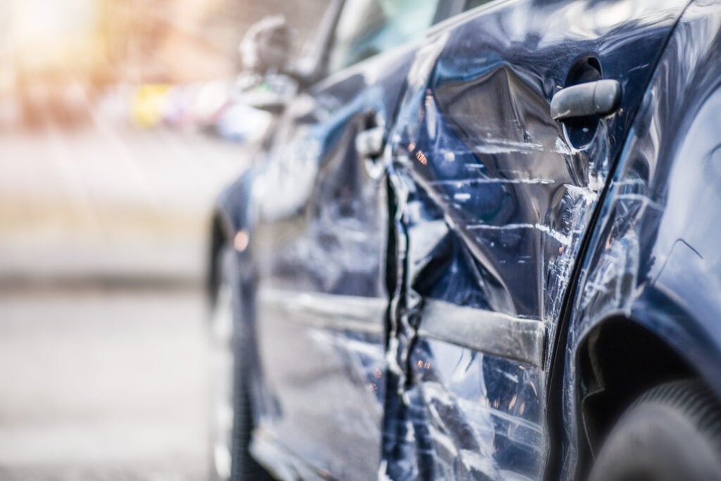 The dented and scraped side of a car that has been in an auto accident