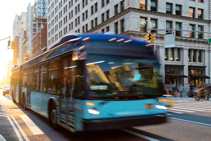 A blue bus driving down a street in a downtown area