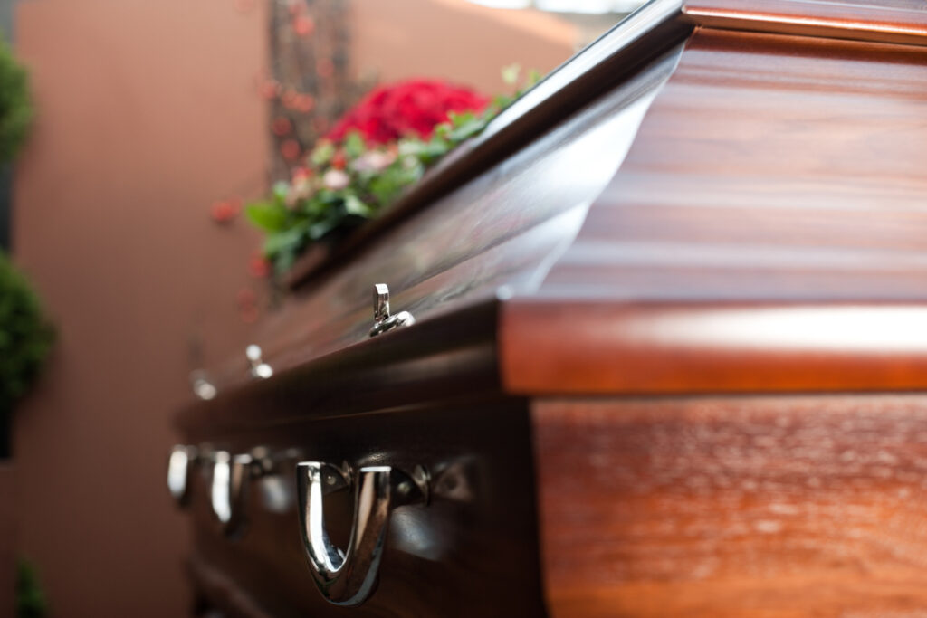 A funeral coffin with a rose on top of it
