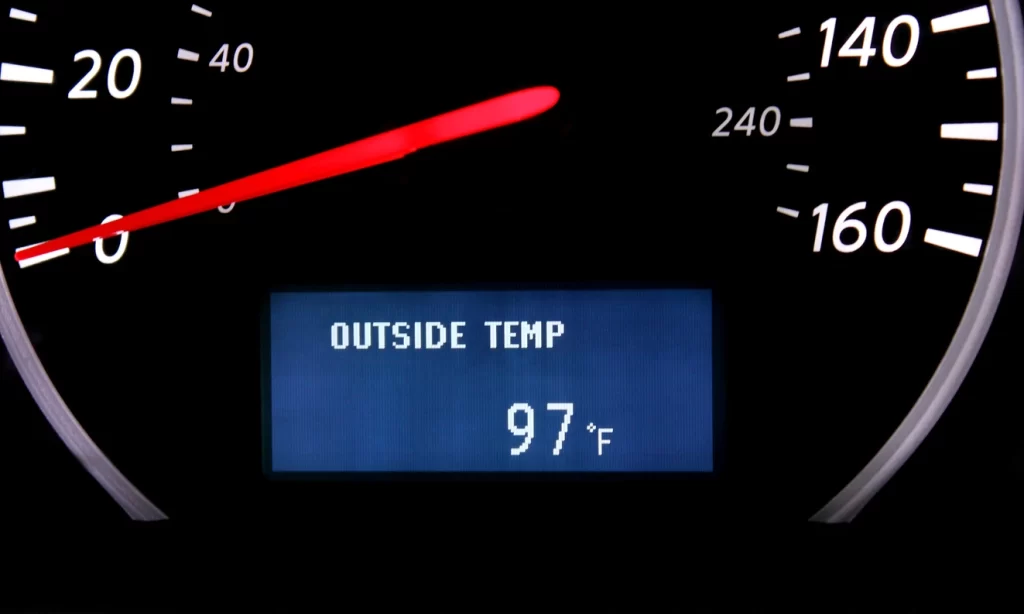 Dashboard thermometer in a car reading 97 degrees Fahrenheit