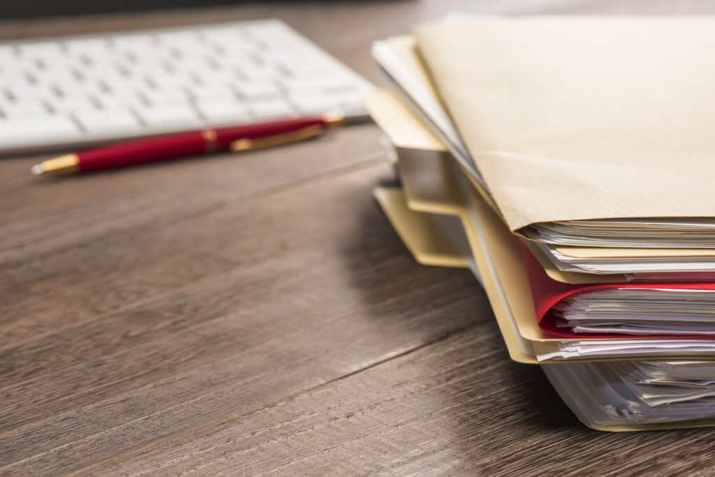 A stack of documents on a desk next to a keyboard