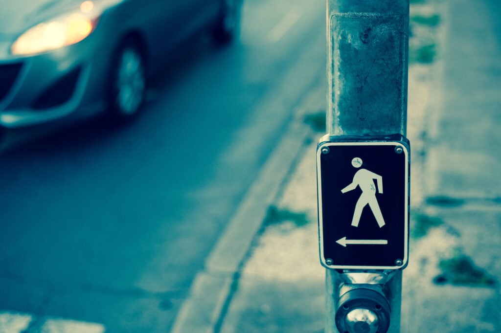 A crosswalk signal button on a street corner
