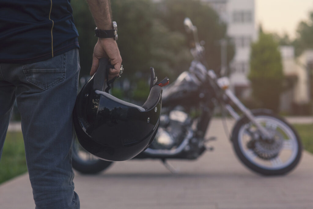 Motorcycle rider standing in front of a motorcycle holding a helmet