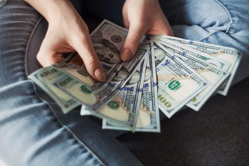 A person holding seven $100 dollar bills