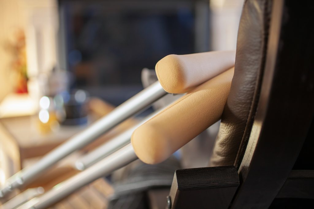 A pair of crutches resting against a leather chair