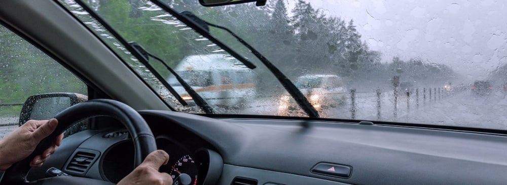 View through the rain-drenched windshield of a car driving on a rainy day on the highway