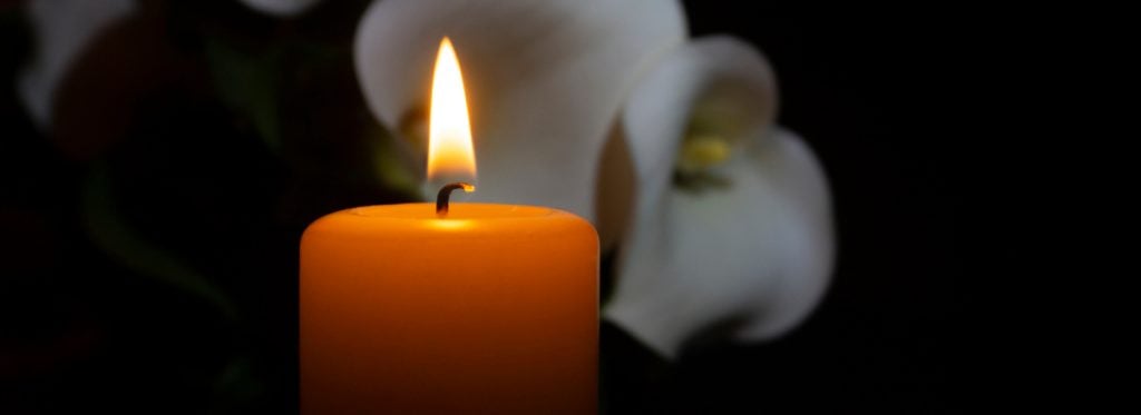 Close up of orange candle flame and lily flowers