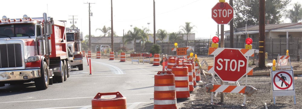 Construction zone on a street with stop signs, warning cones, and a truck