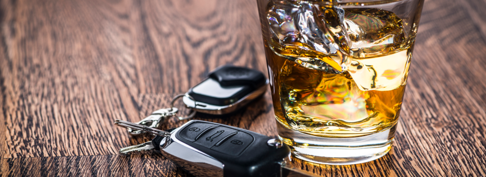 Vignette of car keys on a table next to an alcoholic beverage