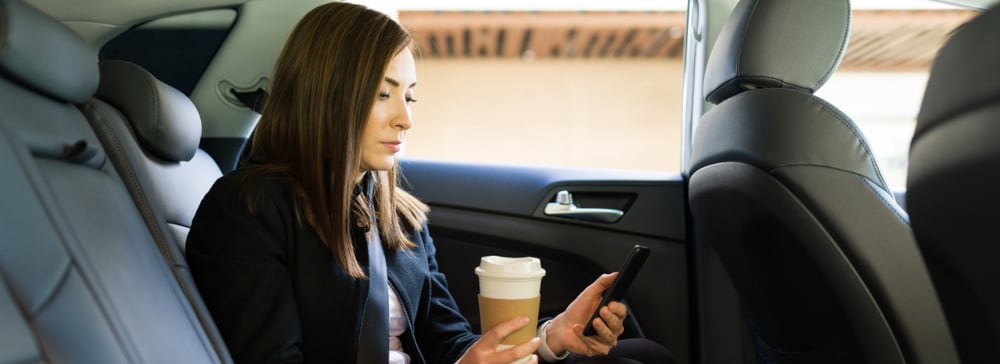 Business woman on her phone in the back seat of an Uber 