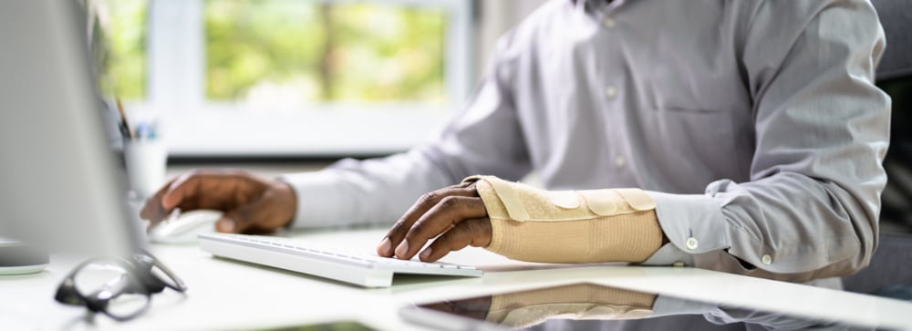 A man with a wrist brace using an office computer