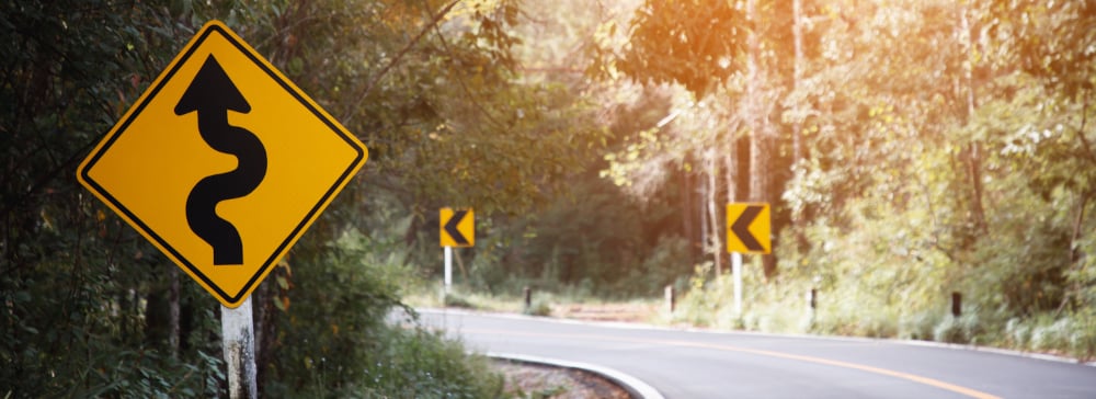 Traffic sign on a road warning of a dangerous curve ahead