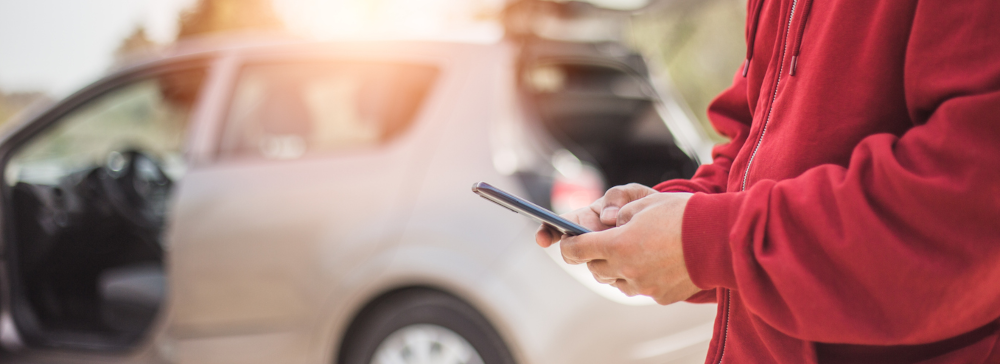 A woman outside of her car texting after an accident