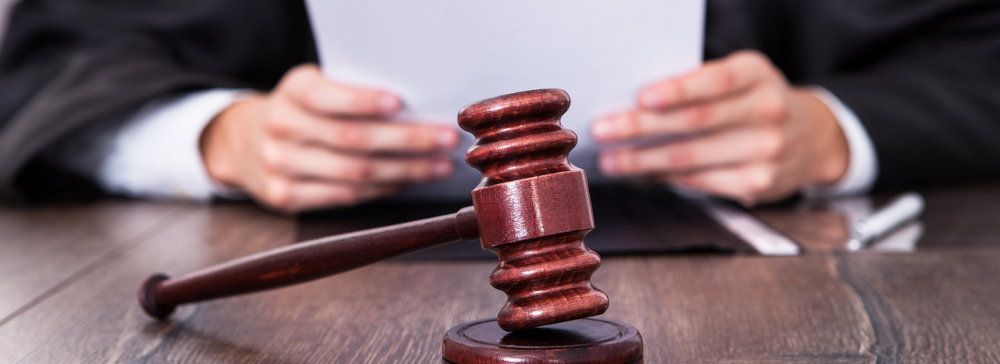 Vignette of a gavel in front of a judge reading from a court order