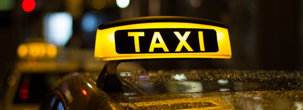 A sign on top of a taxi cab at night in the rain