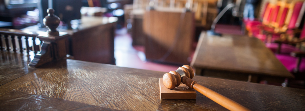 Vignette view of a courtroom from the judge's bench with a gavel in the foreground