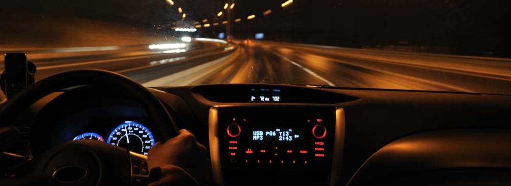 View from the driver's seat of a car driving on the highway at night with motion blur