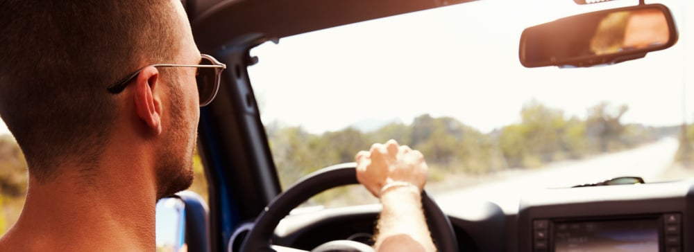 Man with sunglasses driving on a sunny day