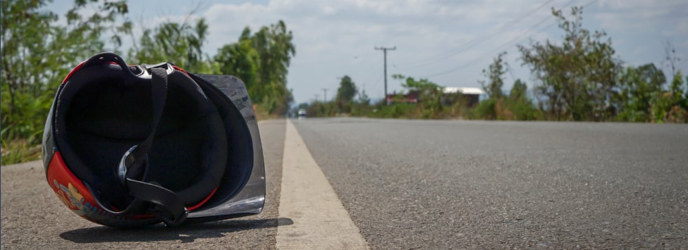 A motorcycle helmet laying by the side of the road after an accident