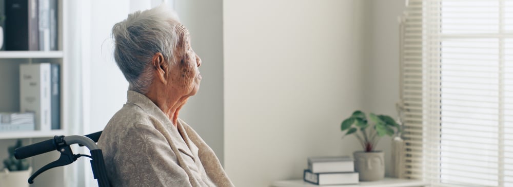 Elderly woman looking out the window in a nursing home