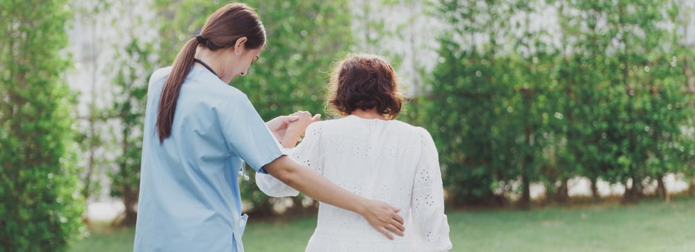 A female nurse guiding an elderly resident in the garden at a nursing home