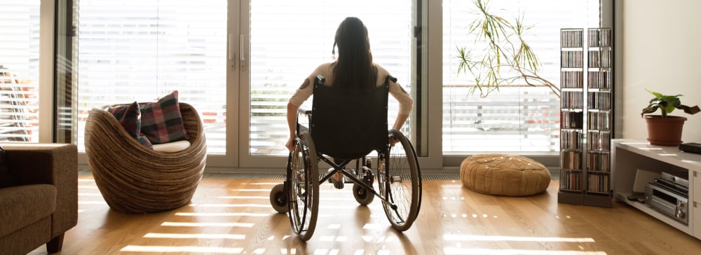 Woman with a spinal cord injury sitting in a wheelchair in front of a window