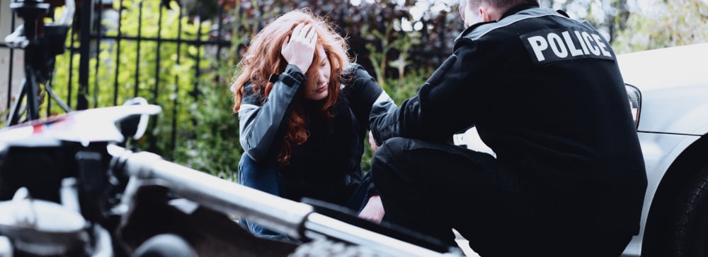 A woman with a head injury after a motorcycle accident being examined by a police officer