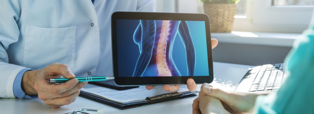 A doctor using a tablet computer to explain a spinal cord injury to a patient