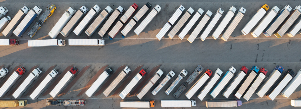 An overhead photograph of numerous semi-trucks parked in a parking lot