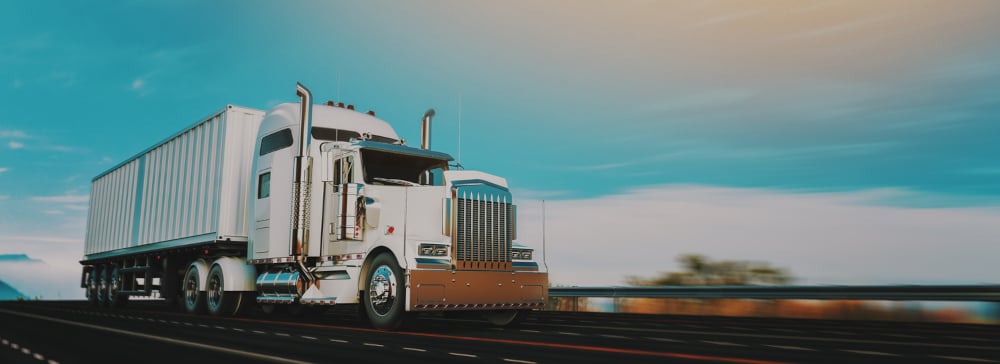 A white semi truck with a trailer driving down the highway