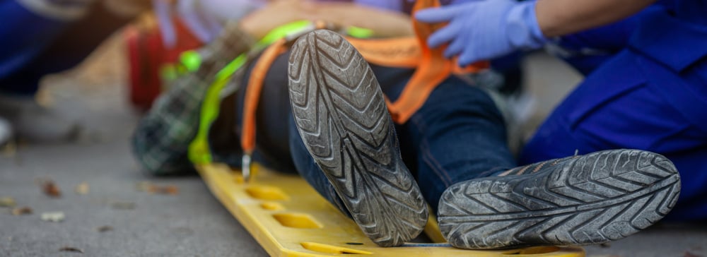 An injured worker strapped to a medical gurney while paramedics work on him