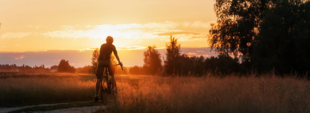 Silhouette of cyclist riding at sunset with trees in the background