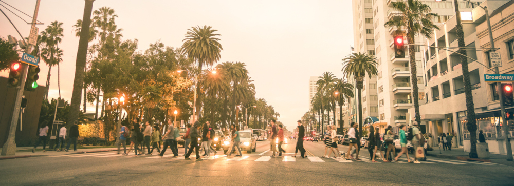 People crossing a crosswalk across a street by the beach