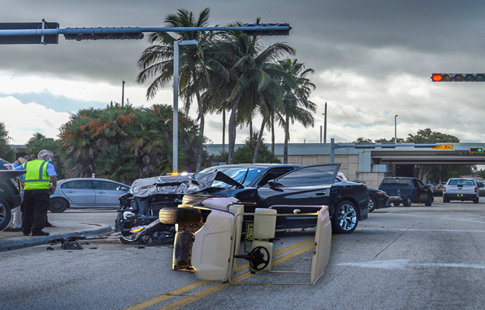 A golf cart on it's side after an accident at a city street intersection