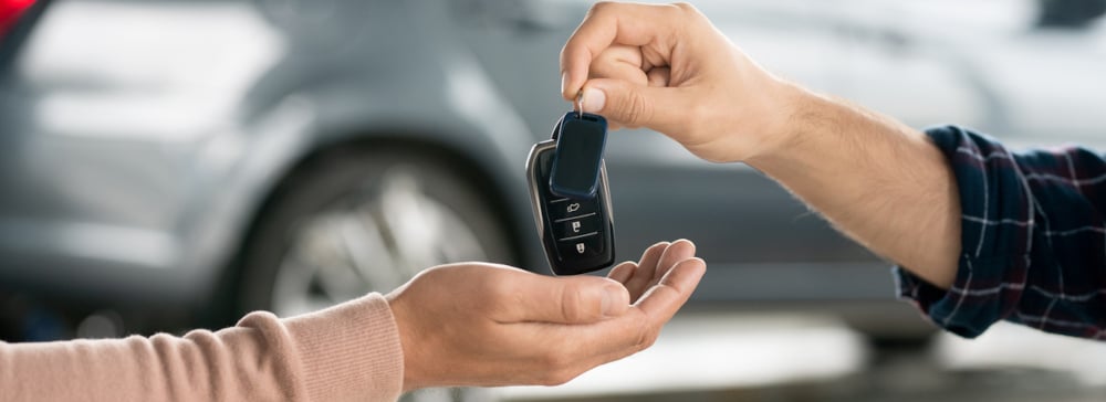 A person handing over car keys to another person