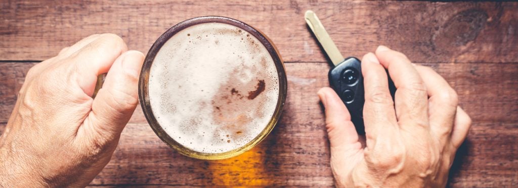 Male hands holding a glass of beer and car keys