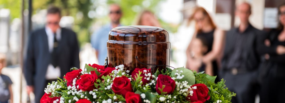 A funerary urn at a funeral with mourners in the background