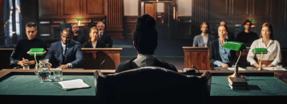 Female judge on the bench in a courtroom with plaintiff and defendant and their lawyers