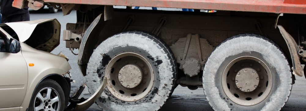 A champagne-colored passenger vehicle that has rear-ended a red industrial truck