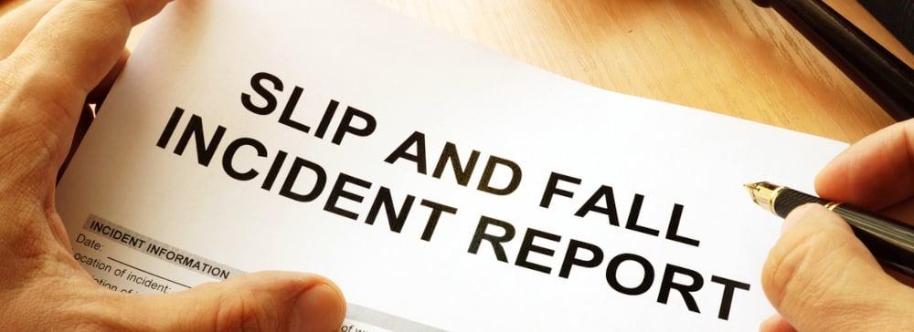 A person writing on a form labeled "Slip and Fall Incident Report"