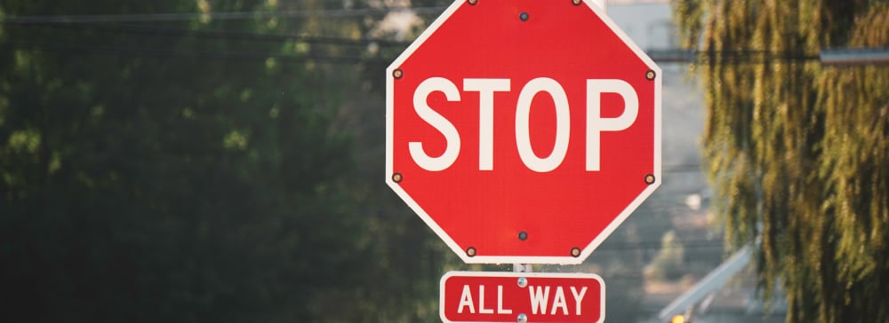 A red four-way stop sign in the city. 