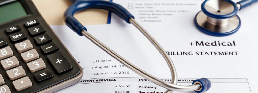 A stethoscope and calculator on top of a printed medical bill