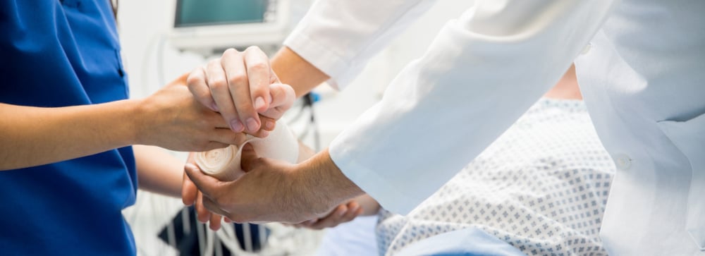 A doctor and nurse putting a bandage on a patient's burn injury in the hospital